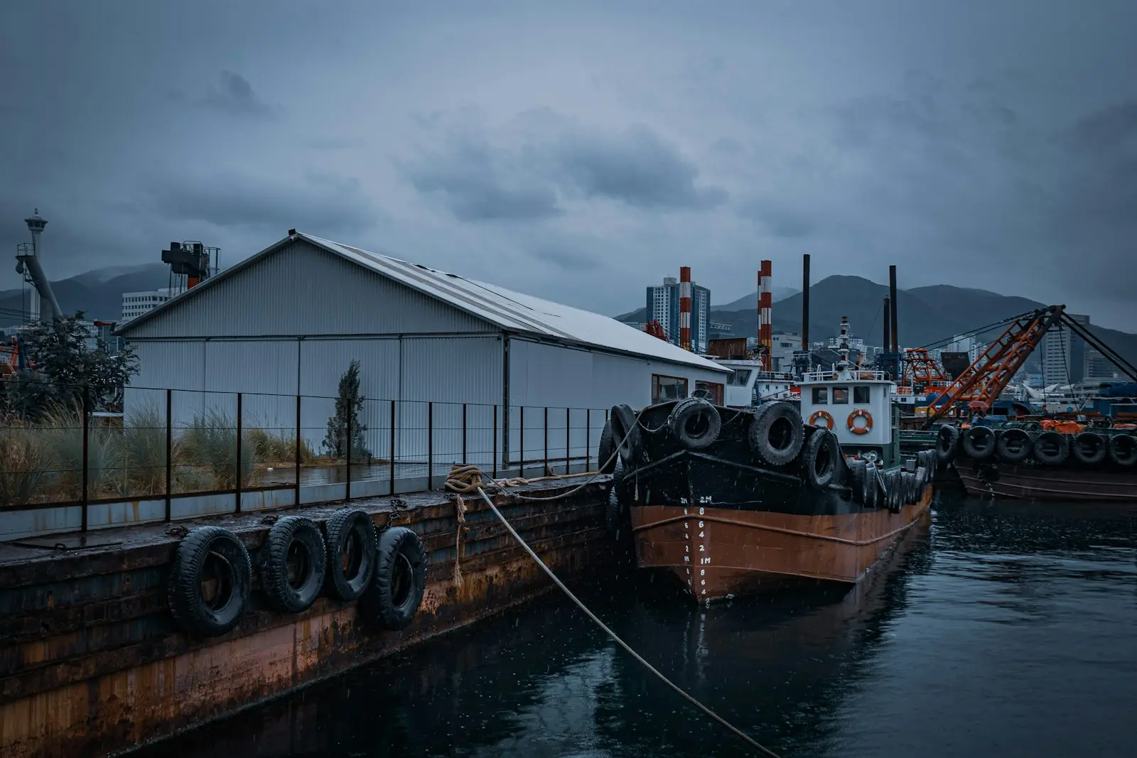 Kapalı havada lastik usturmaçalı rıhtım kenarı, bağlı römorkör ve durgun deniz